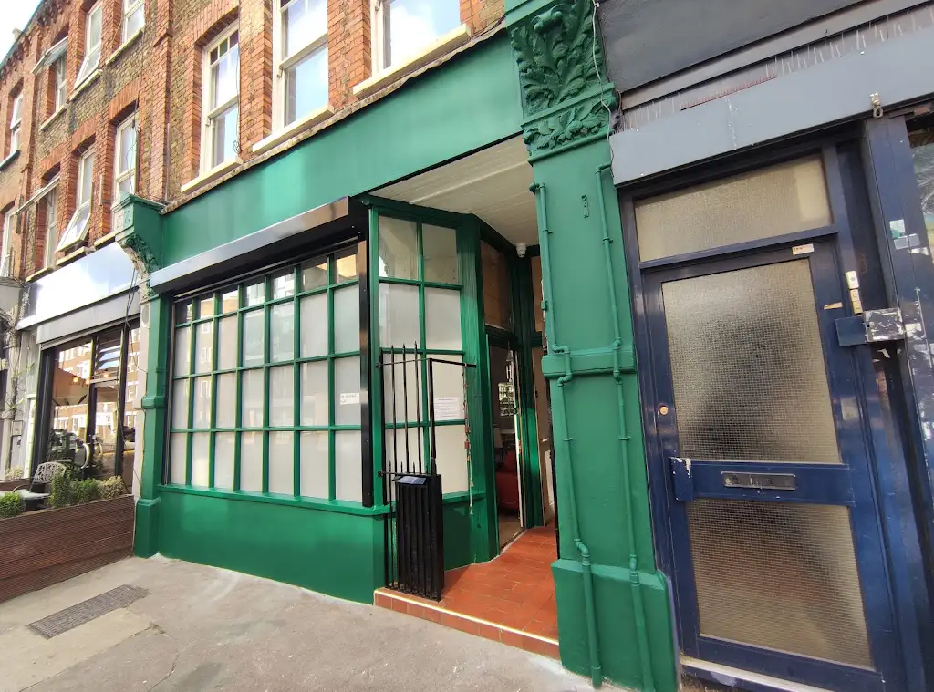 Commercial shopfront painted in deep green with ornate period details