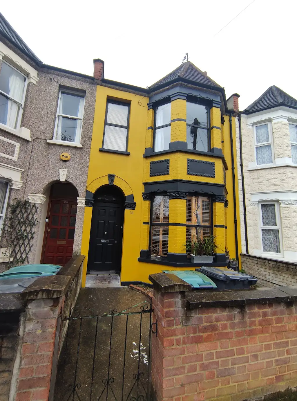 Bold yellow painted Victorian terraced house with dark window frames