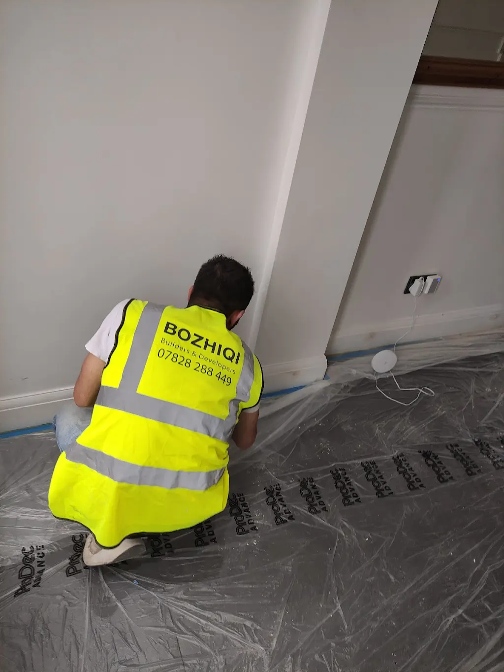 Bozhiqi decorator carefully painting skirting boards with dust sheets down